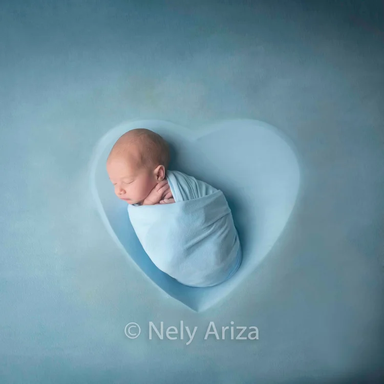 Fotografía de bebé recién nacido dentro de un corazón decorativo.