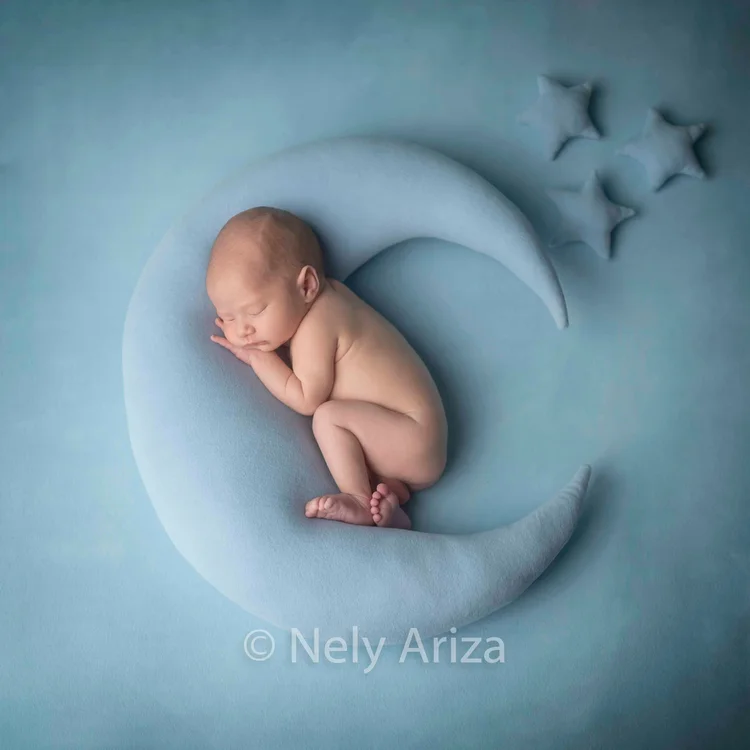 Foto de bebé recién nacido dentro de una luna decorativa.